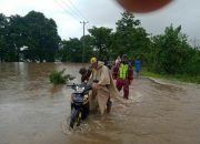 Aksi Babinsa Koramil 1426-07/Pattallassang Bantu Warga Melintasi Jalan Akibat Banjir